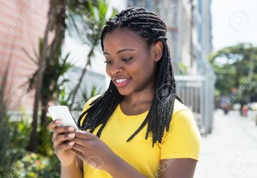 50825651-african-american-woman-in-a-yellow-shirt-texting-message-with-mobile-phone-stock-photo